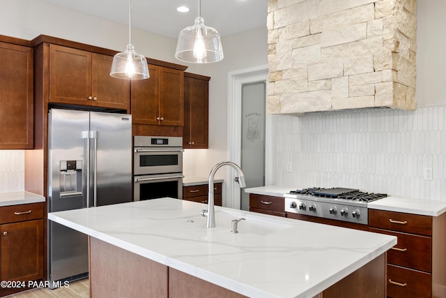 kitchen with light stone countertops, sink, hanging light fixtures, light hardwood / wood-style floors, and appliances with stainless steel finishes