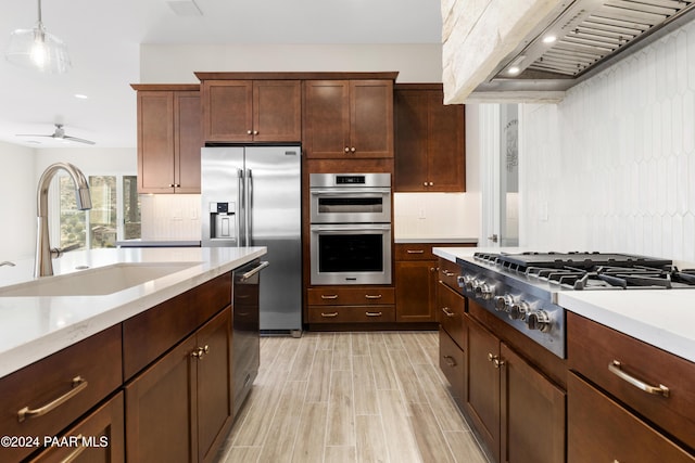 kitchen featuring appliances with stainless steel finishes, premium range hood, ceiling fan, sink, and pendant lighting