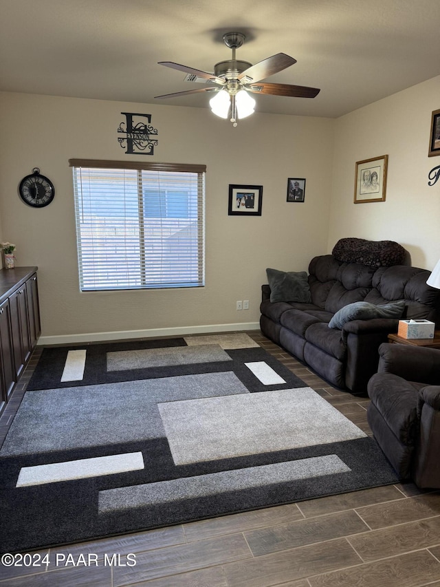 living room featuring ceiling fan and dark wood-type flooring