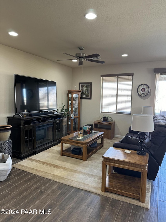 living room featuring a textured ceiling, ceiling fan, and a healthy amount of sunlight