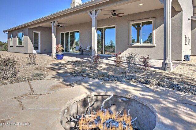 rear view of property featuring stucco siding, ceiling fan, and a patio