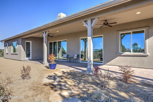 rear view of house with a patio, a chimney, ceiling fan, and stucco siding