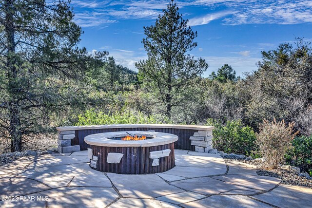 view of patio featuring a fire pit and a view of trees