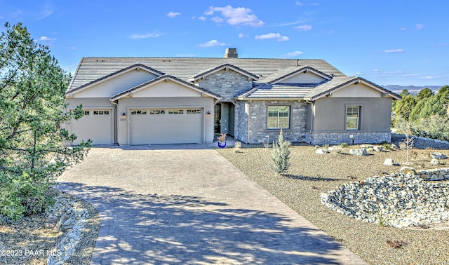 single story home featuring a chimney, a garage, stucco siding, a tile roof, and driveway