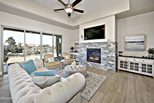 living room with wood finished floors, ceiling fan, and a glass covered fireplace