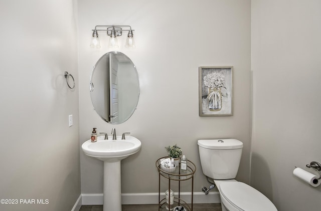 bathroom featuring baseboards, toilet, and a sink