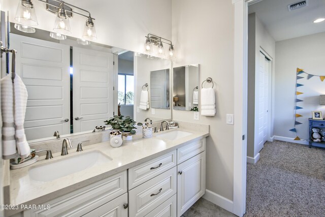full bath with baseboards, visible vents, double vanity, and a sink