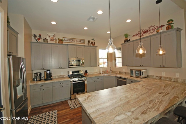 8737 N Mare St, Prescott Valley, AZ 86315 - kitchen with stainless steel appliances, a peninsula, a sink, gray cabinets, and a breakfast bar area