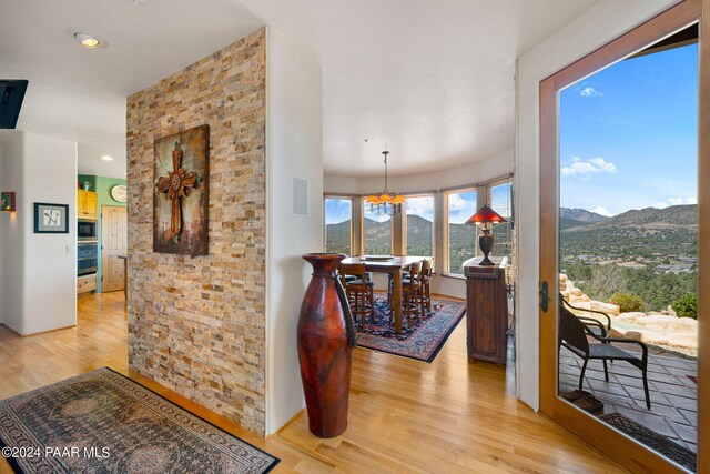 corridor with a mountain view, light hardwood / wood-style flooring, and a chandelier