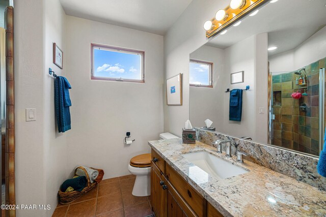 bathroom with tile patterned flooring, vanity, toilet, and a shower with door