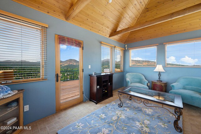 living area featuring a mountain view, lofted ceiling with beams, a wealth of natural light, and wood ceiling