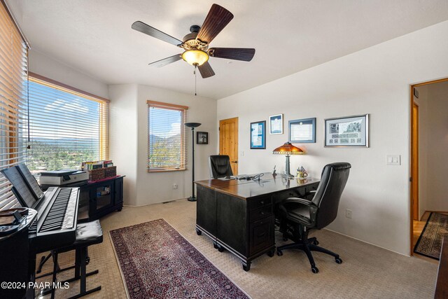 carpeted home office with a wealth of natural light and ceiling fan