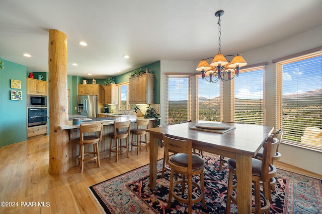 dining space featuring light wood-type flooring, sink, and a chandelier