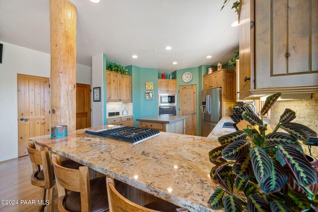 kitchen with a center island, stainless steel appliances, tasteful backsplash, light hardwood / wood-style flooring, and kitchen peninsula