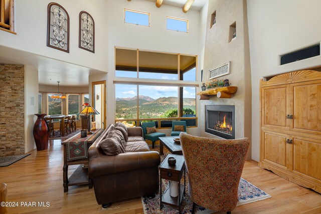 living room featuring a mountain view, a large fireplace, light hardwood / wood-style floors, and a high ceiling