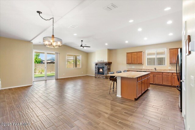 1364 Towhee Trl, Prescott, AZ 86305 - kitchen featuring open floor plan, a fireplace, a center island, a ceiling fan, and a breakfast bar area