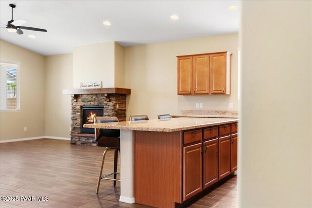 1364 Towhee Trl, Prescott, AZ 86305 - kitchen featuring a breakfast bar area, dark wood-style floors, a stone fireplace, a ceiling fan, and recessed lighting