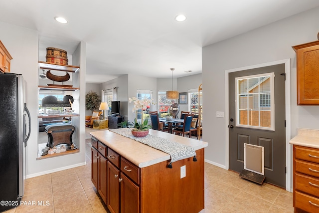 kitchen featuring hanging light fixtures, light tile patterned floors, a kitchen island, and stainless steel fridge