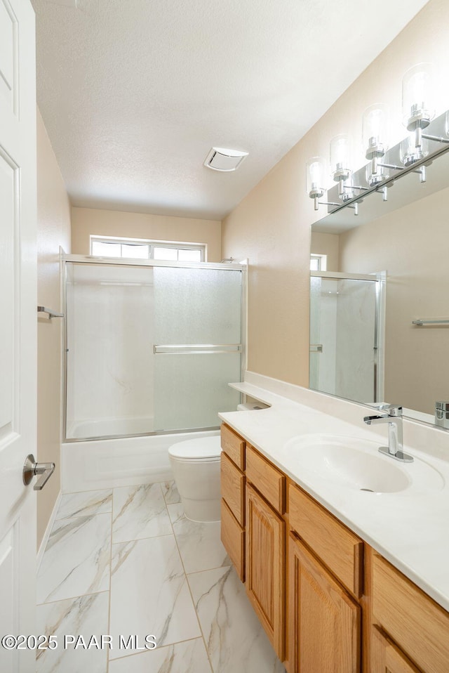 bathroom featuring vanity, toilet, marble finish floor, and a textured ceiling