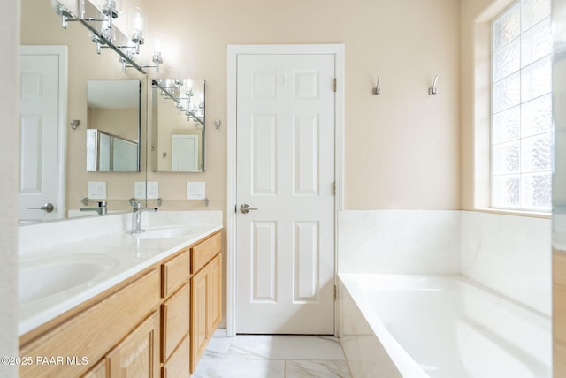 full bath featuring a sink, a garden tub, marble finish floor, and double vanity