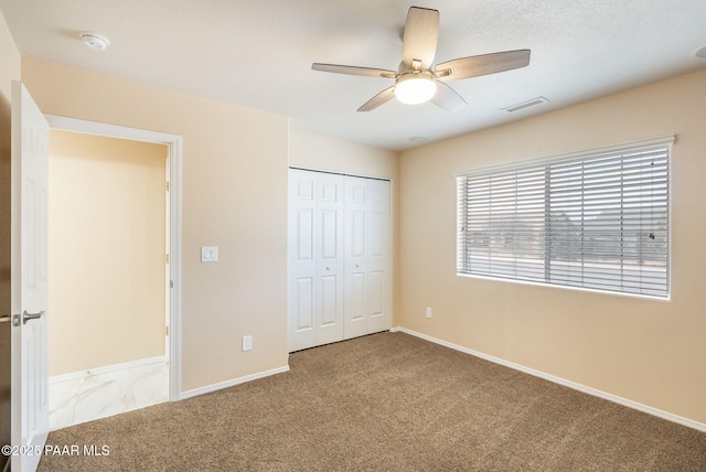 unfurnished bedroom featuring visible vents, baseboards, ceiling fan, carpet flooring, and a closet