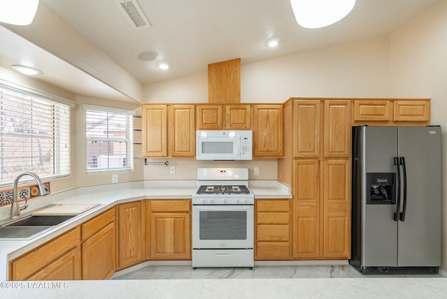 kitchen featuring white appliances, visible vents, a sink, vaulted ceiling, and light countertops