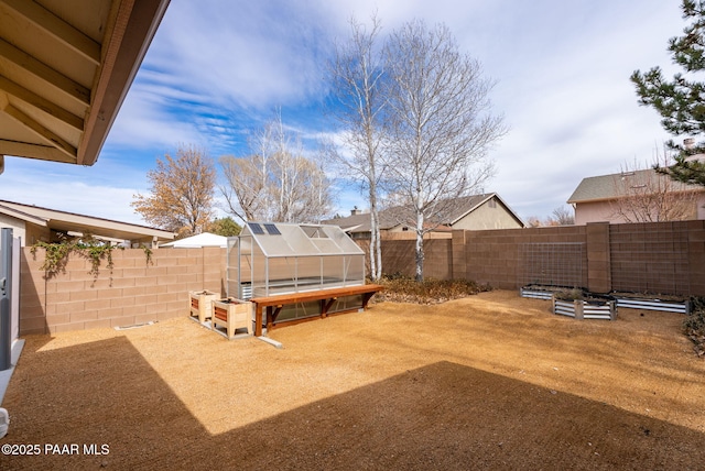 view of yard featuring an outbuilding, a fenced backyard, and an exterior structure