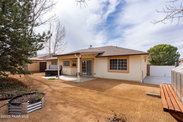 rear view of house with stucco siding, a fenced backyard, a patio area, a shingled roof, and a hot tub