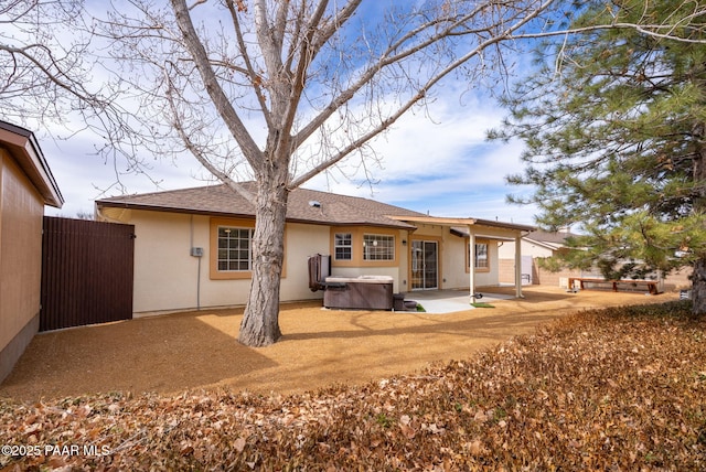 back of house with a patio area, stucco siding, a hot tub, and fence