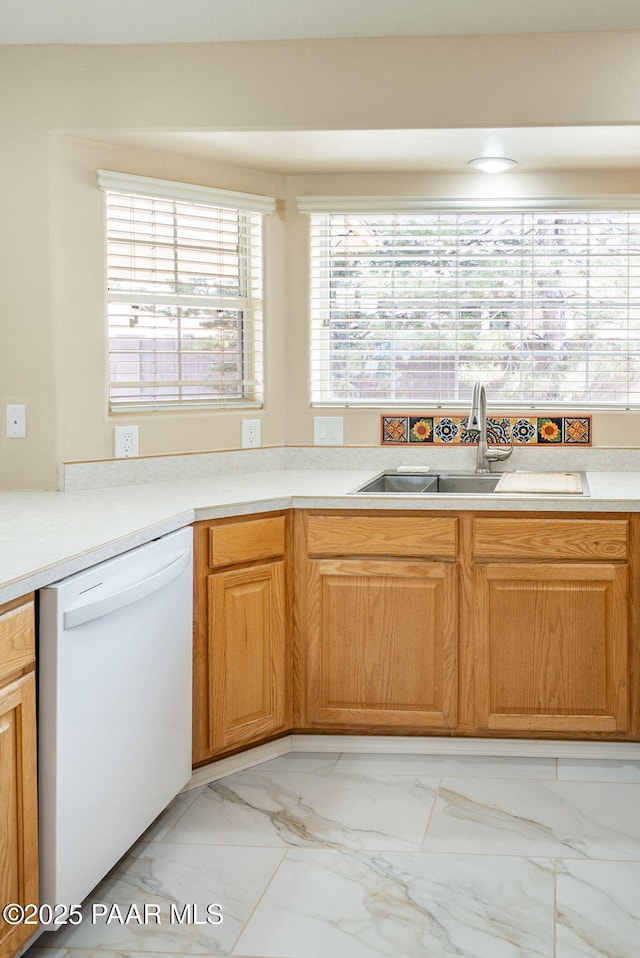 kitchen with dishwasher, light countertops, marble finish floor, and a sink