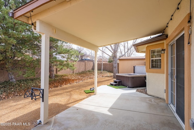 view of patio / terrace featuring a hot tub and fence