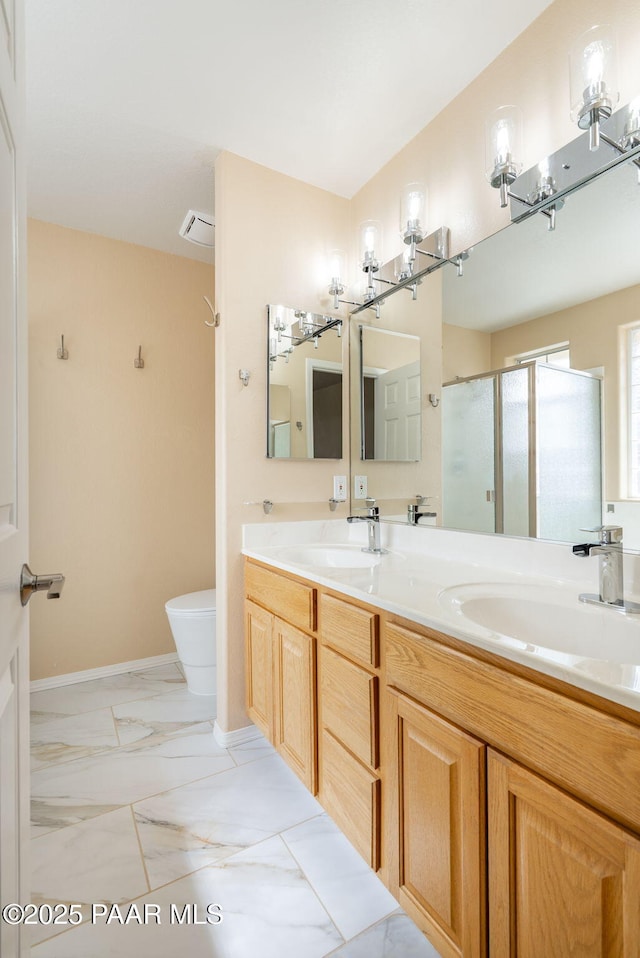 full bathroom with a shower stall, double vanity, marble finish floor, and a sink