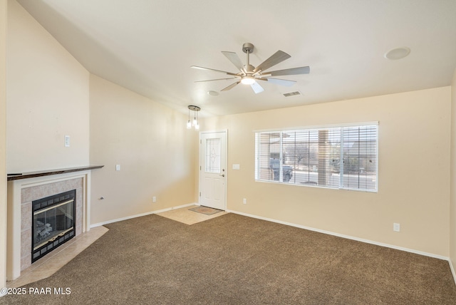 unfurnished living room with light carpet, visible vents, a tile fireplace, and baseboards