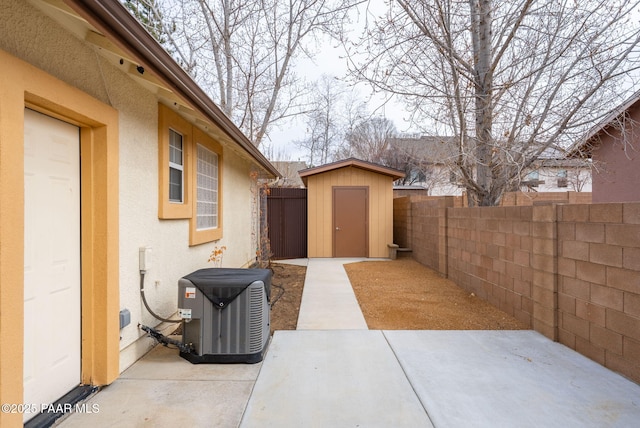 view of patio / terrace featuring a fenced backyard, a storage unit, central AC, and an outdoor structure