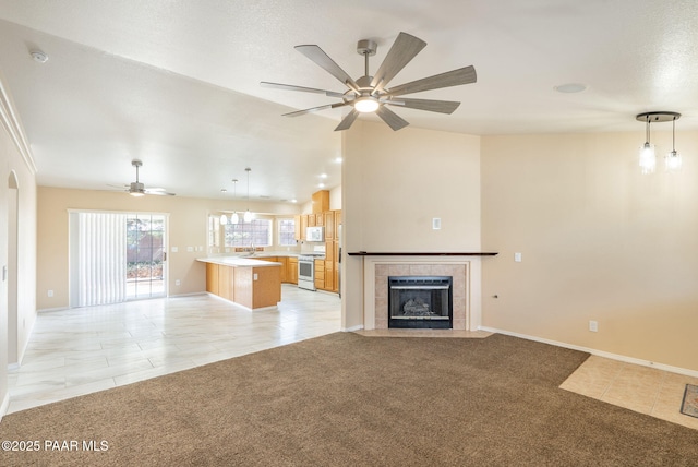 unfurnished living room with a sink, light carpet, a tiled fireplace, and vaulted ceiling