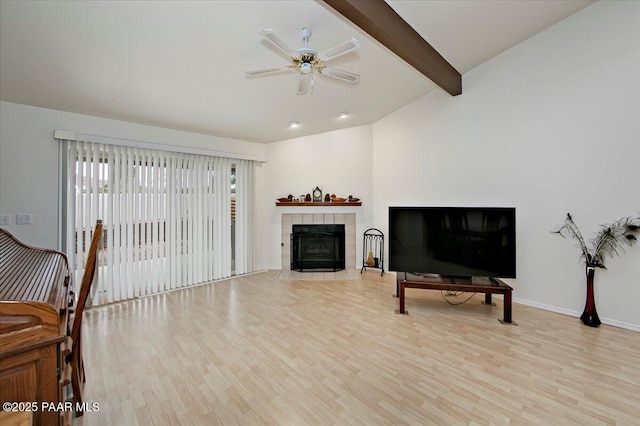 living area with baseboards, lofted ceiling with beams, a fireplace, ceiling fan, and light wood-type flooring