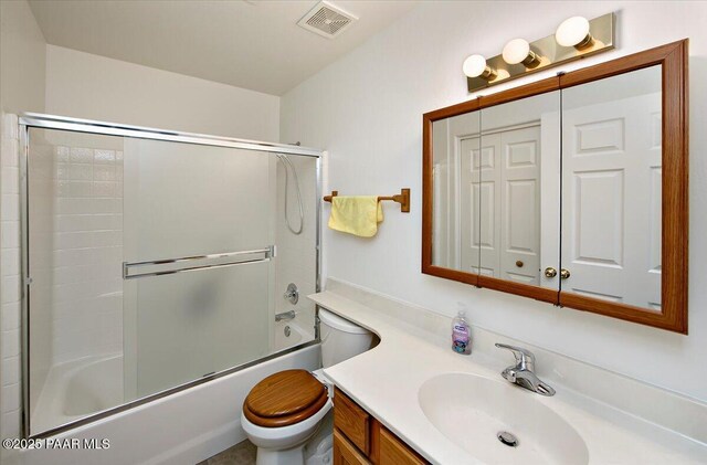 bathroom with vanity, toilet, visible vents, and shower / bath combination with glass door