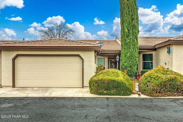 view of front of house with a tiled roof, a garage, and stucco siding