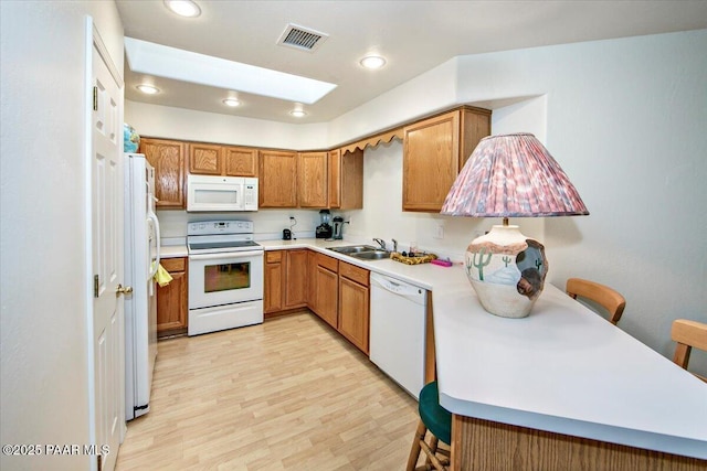 kitchen featuring white appliances, brown cabinetry, visible vents, recessed lighting, and light countertops