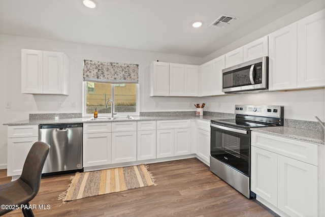 kitchen with white cabinetry, sink, stainless steel appliances, and light stone counters