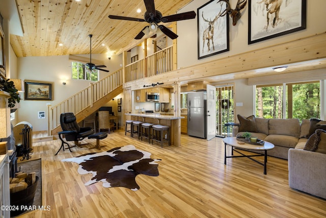 living area with light wood-style flooring, a ceiling fan, stairway, a high ceiling, and wood ceiling