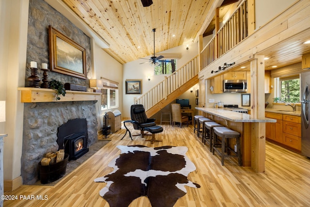 living room featuring ceiling fan, stairway, light wood-type flooring, wooden ceiling, and high vaulted ceiling