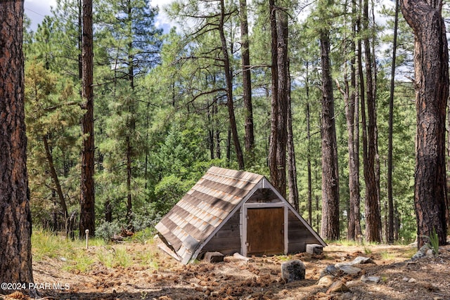 view of outdoor structure featuring an outbuilding and a forest view