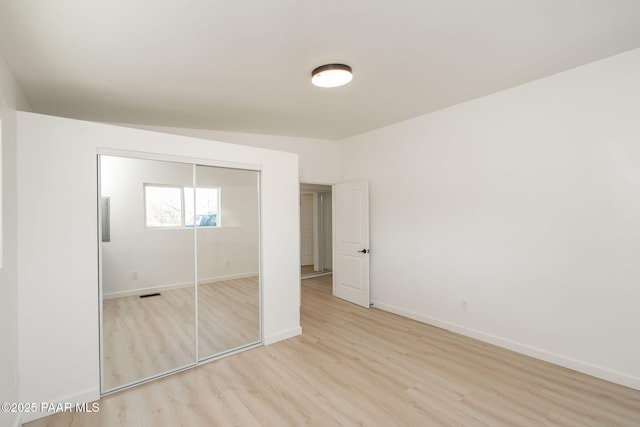 unfurnished bedroom with light hardwood / wood-style flooring and a closet