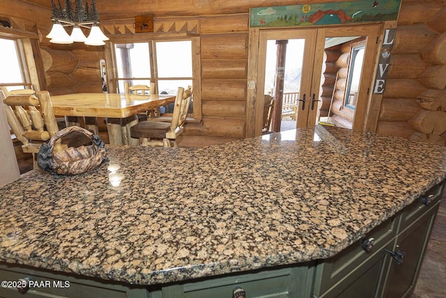 interior space with log walls, french doors, and green cabinetry