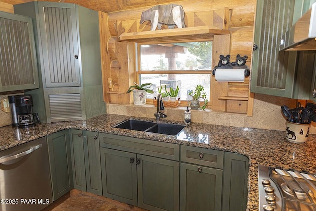 kitchen featuring sink, appliances with stainless steel finishes, wooden walls, and dark stone countertops