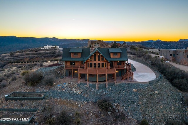 back house at dusk with a deck with mountain view