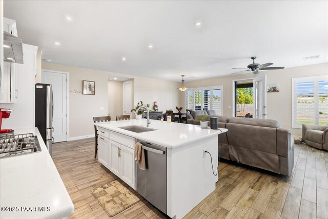 kitchen with white cabinets, light wood-style flooring, stainless steel appliances, and a sink