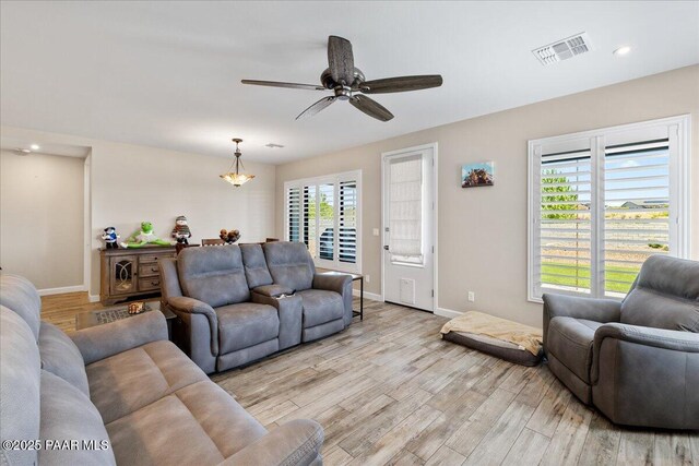 living room with light wood-style flooring, baseboards, visible vents, recessed lighting, and ceiling fan with notable chandelier