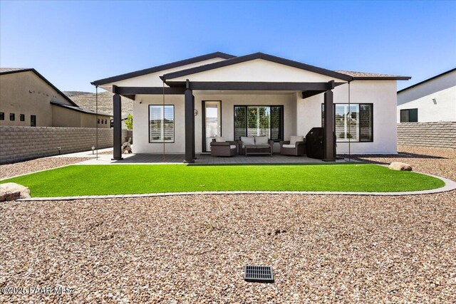 rear view of property featuring stucco siding, outdoor lounge area, a patio area, and a fenced backyard